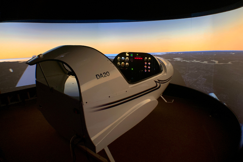 DA20 flight simulator pod inside its dome projection display, with a dusk sky rendered on the screen